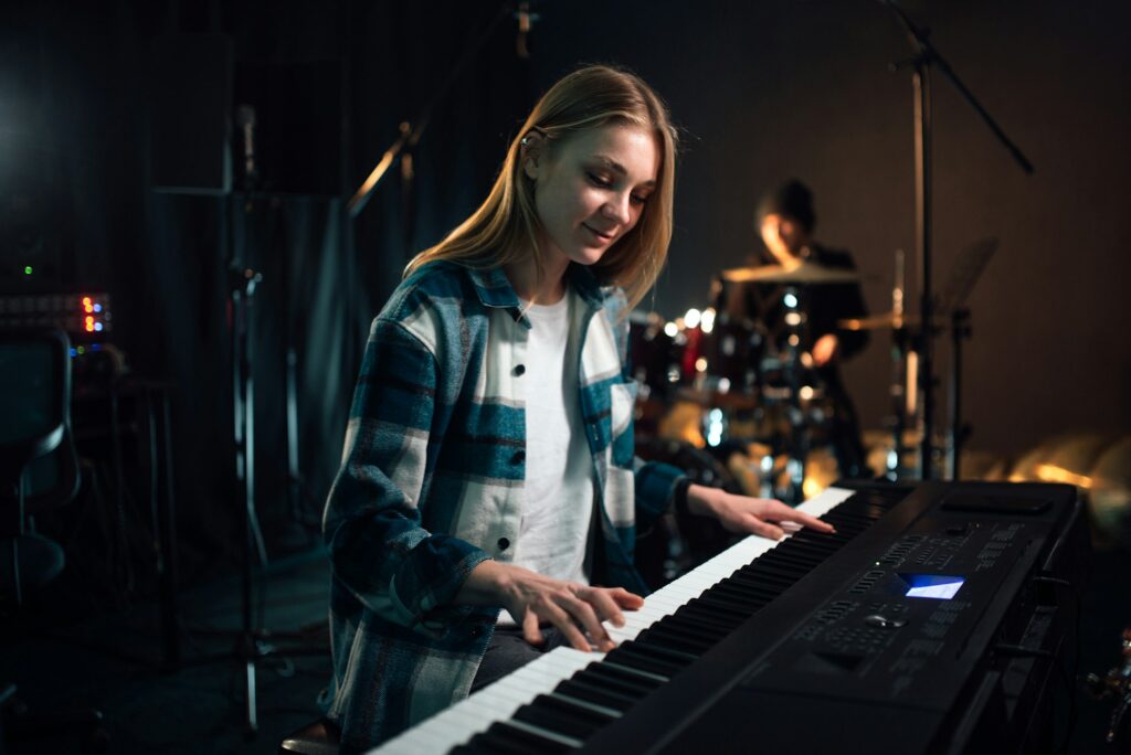 Girl playing the synthesizer. Music creation in a recording studio.