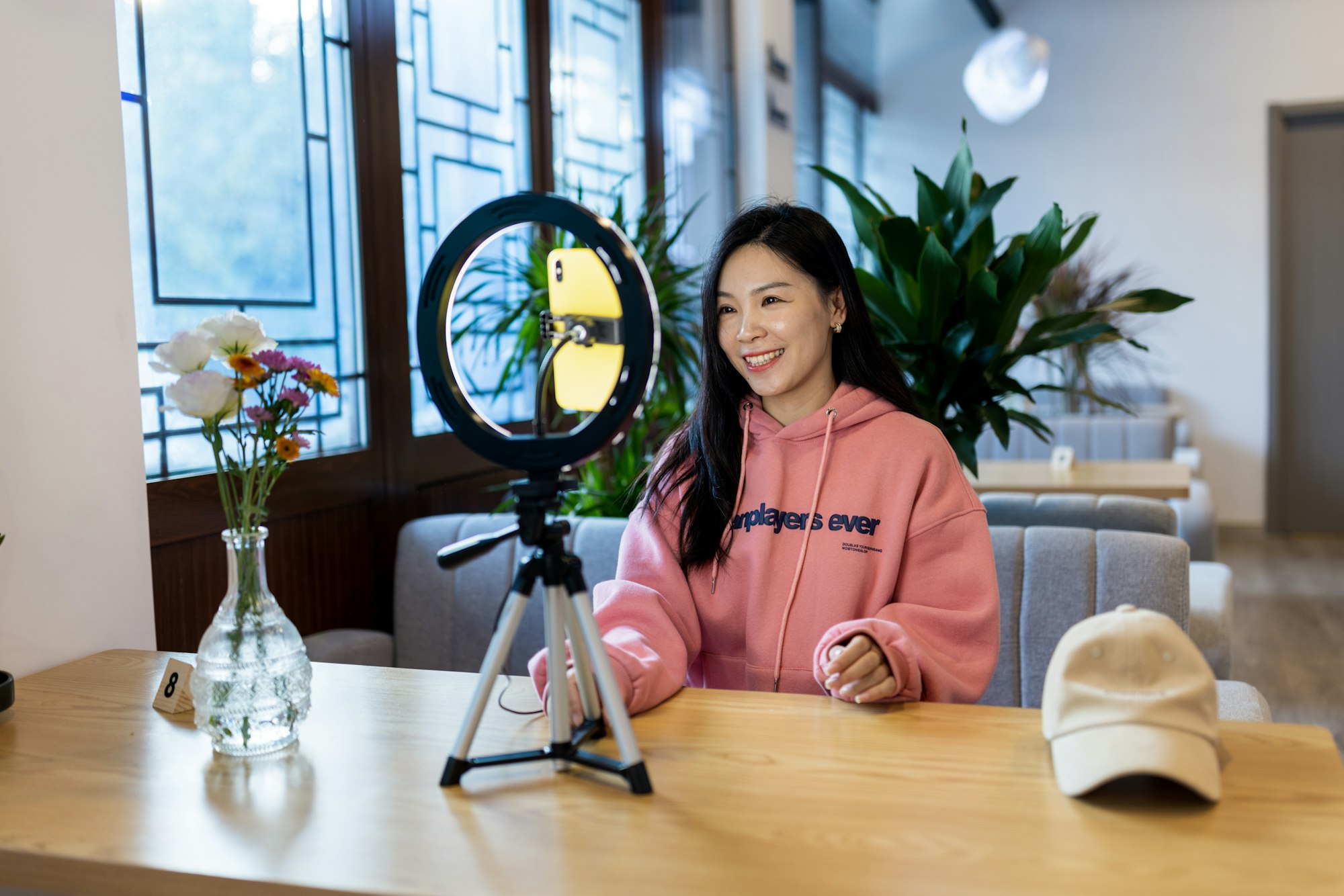 Happy stylish young asian generation z woman using technology in small cafeteria at fall season