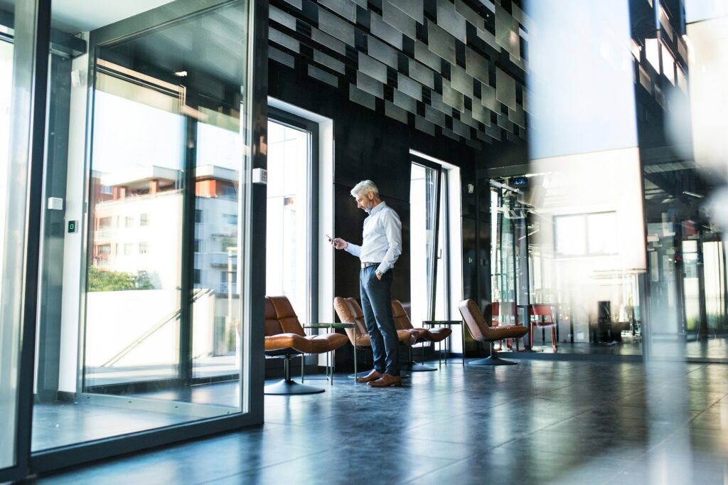 Mature businessman with smartphone in the office.