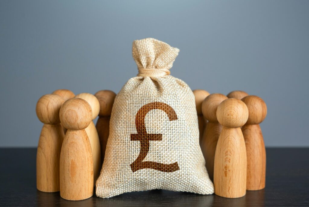 People figures stand around british pound sterling money bag.