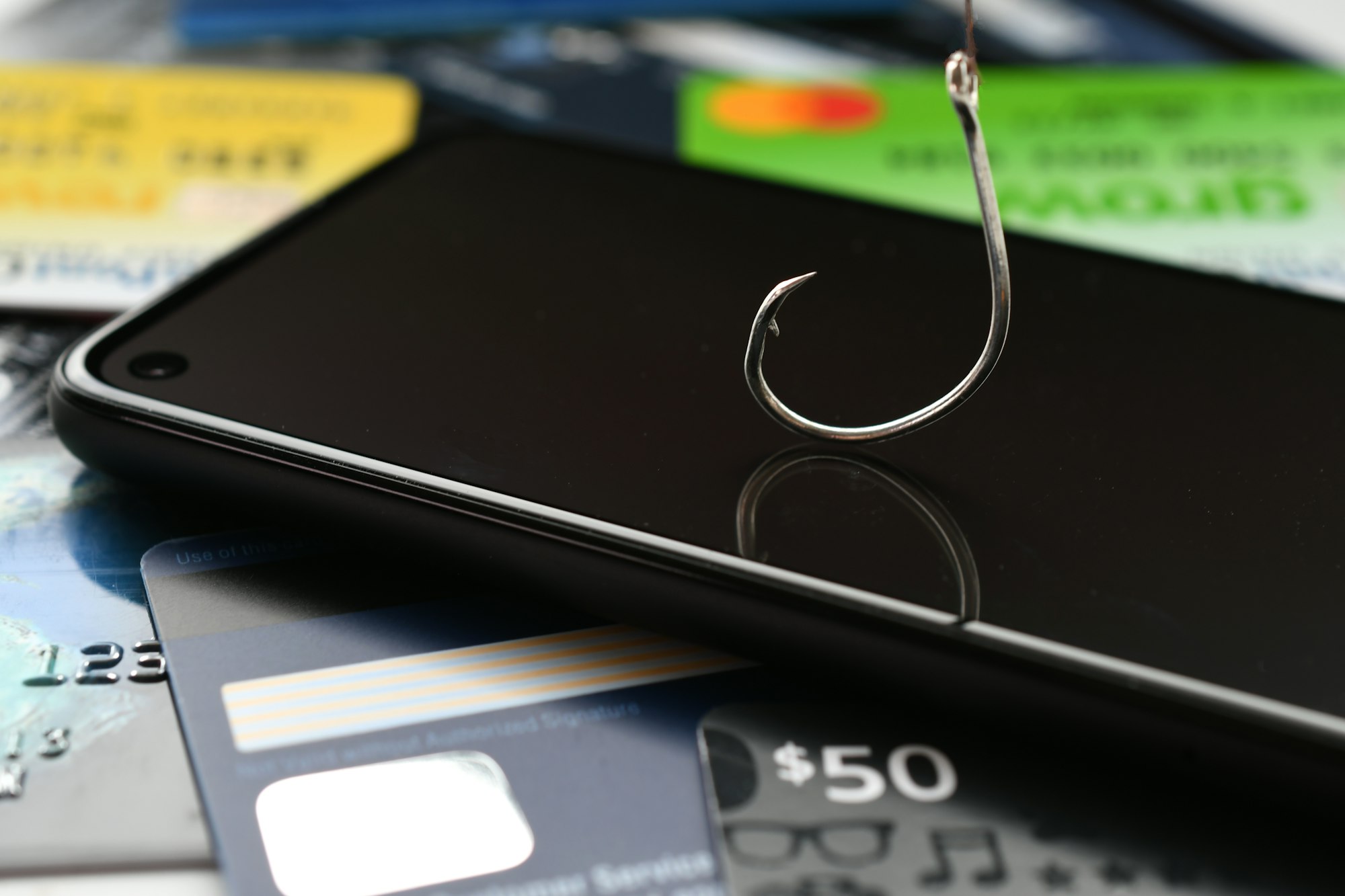 phishing phone call scams vishing concept. cellphone with fishing hook, credit cards & gift cards
