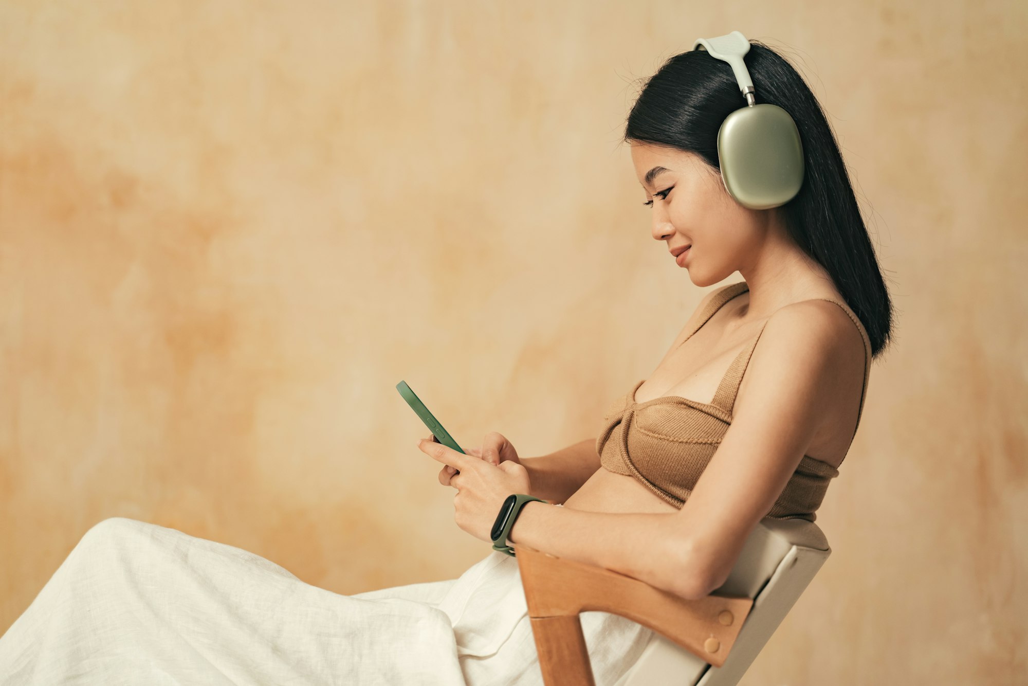 Side view of asian millennial girl in headphones video chatting with her boyfriend using phone app