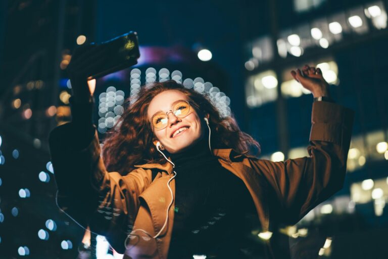 woman in glasses wearing light coat listens to music