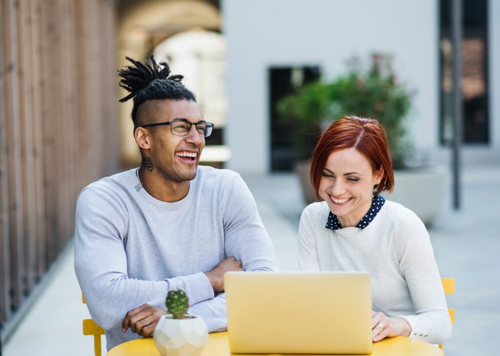 Young businesspeople with laptop in courtyard, start-up concept