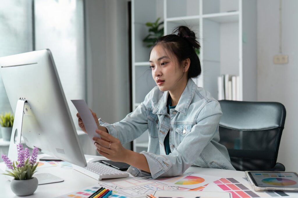 Young Creative Designer Working on Computer in Modern Office with Color Samples and Digital Tools