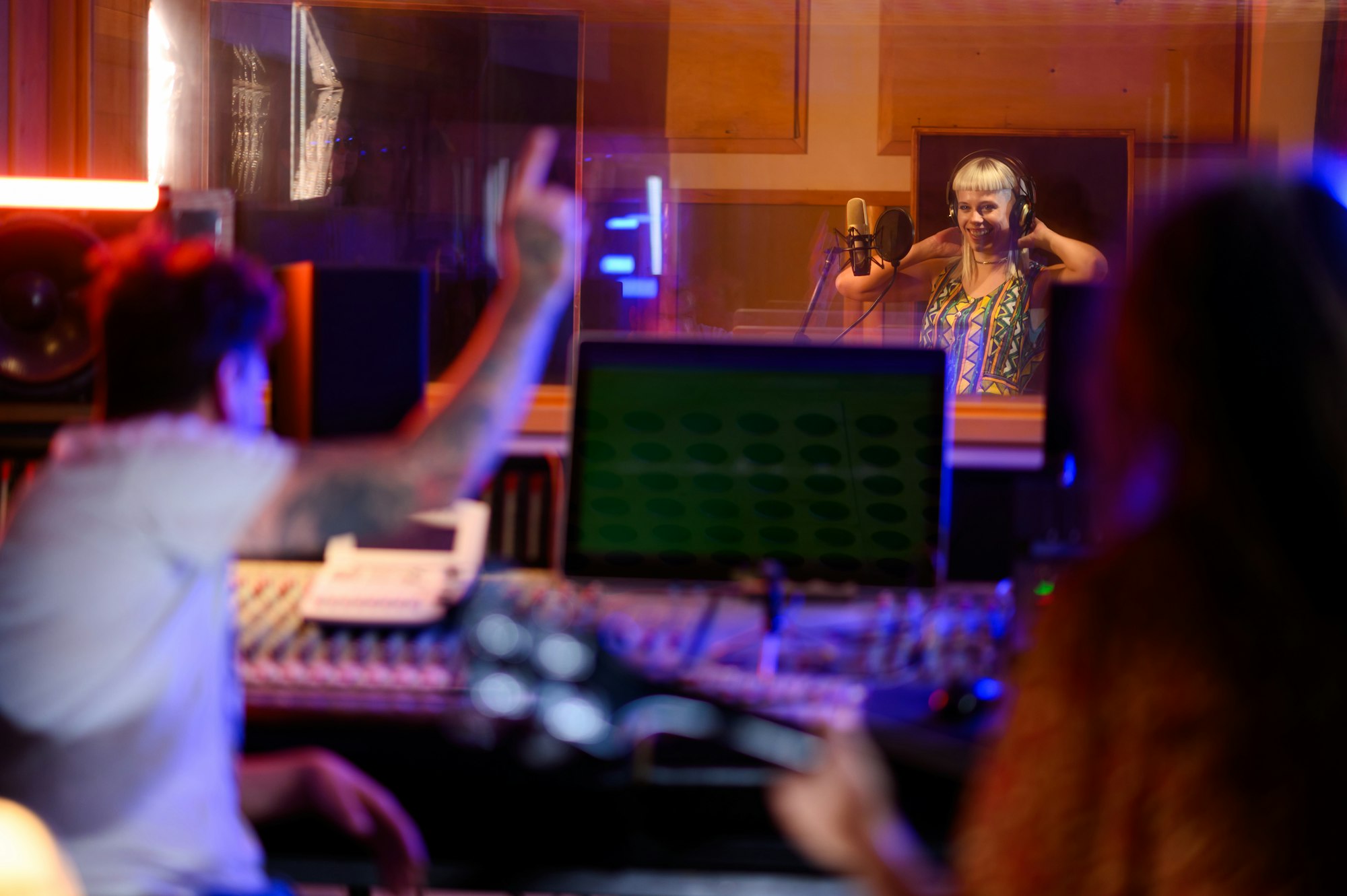 A singer in an isolation room, about to start recording her voice in a music studio.