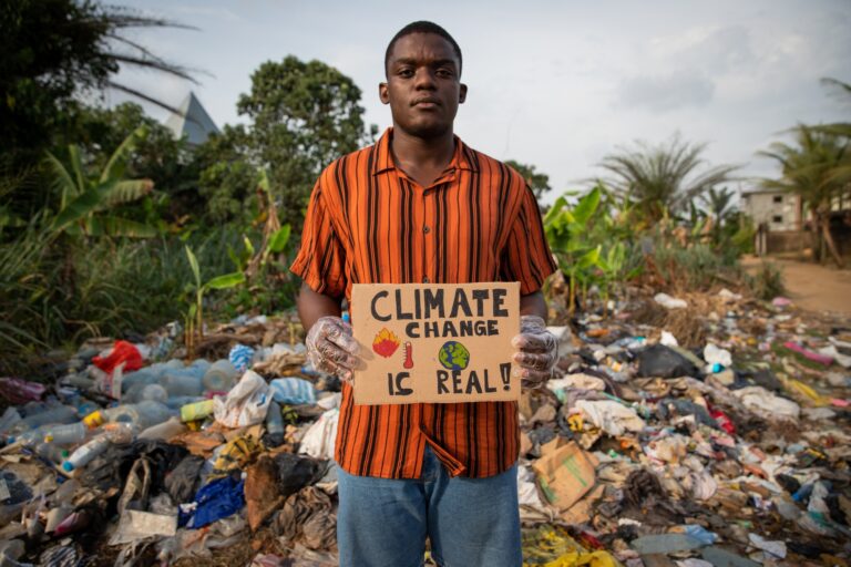 African boy holds a sign in his hand with the words: "climate change is real" and protests