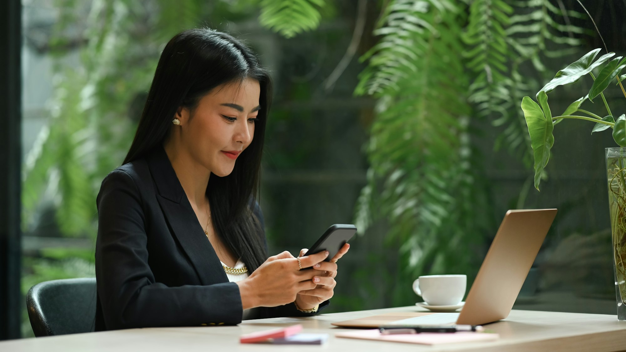 Asian working woman texting text message on her smart phone, working in modern office.