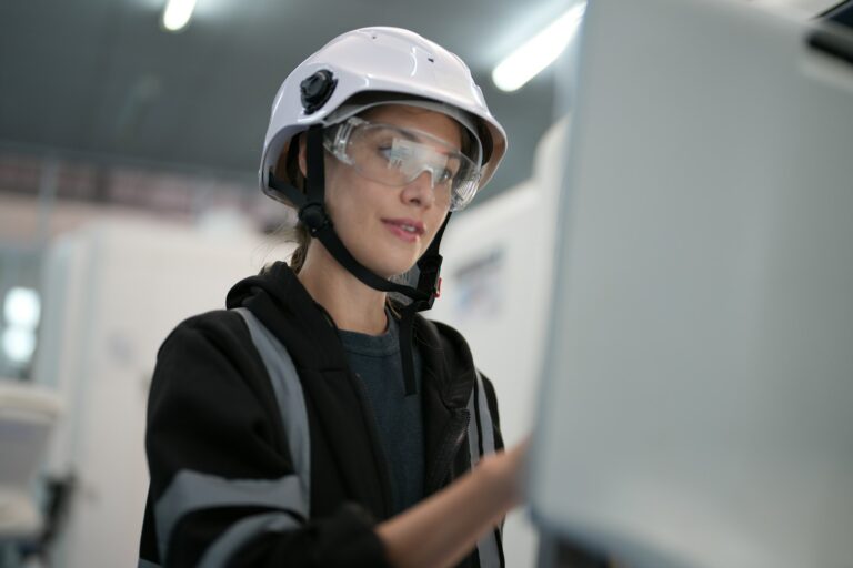 Female technician programs a robot arm with a digital tablet and assembly robot in a factory