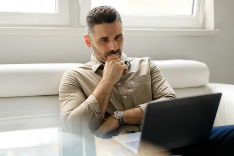 Focused thoughtful businessman using laptop and thinking of project, making decision, looking at