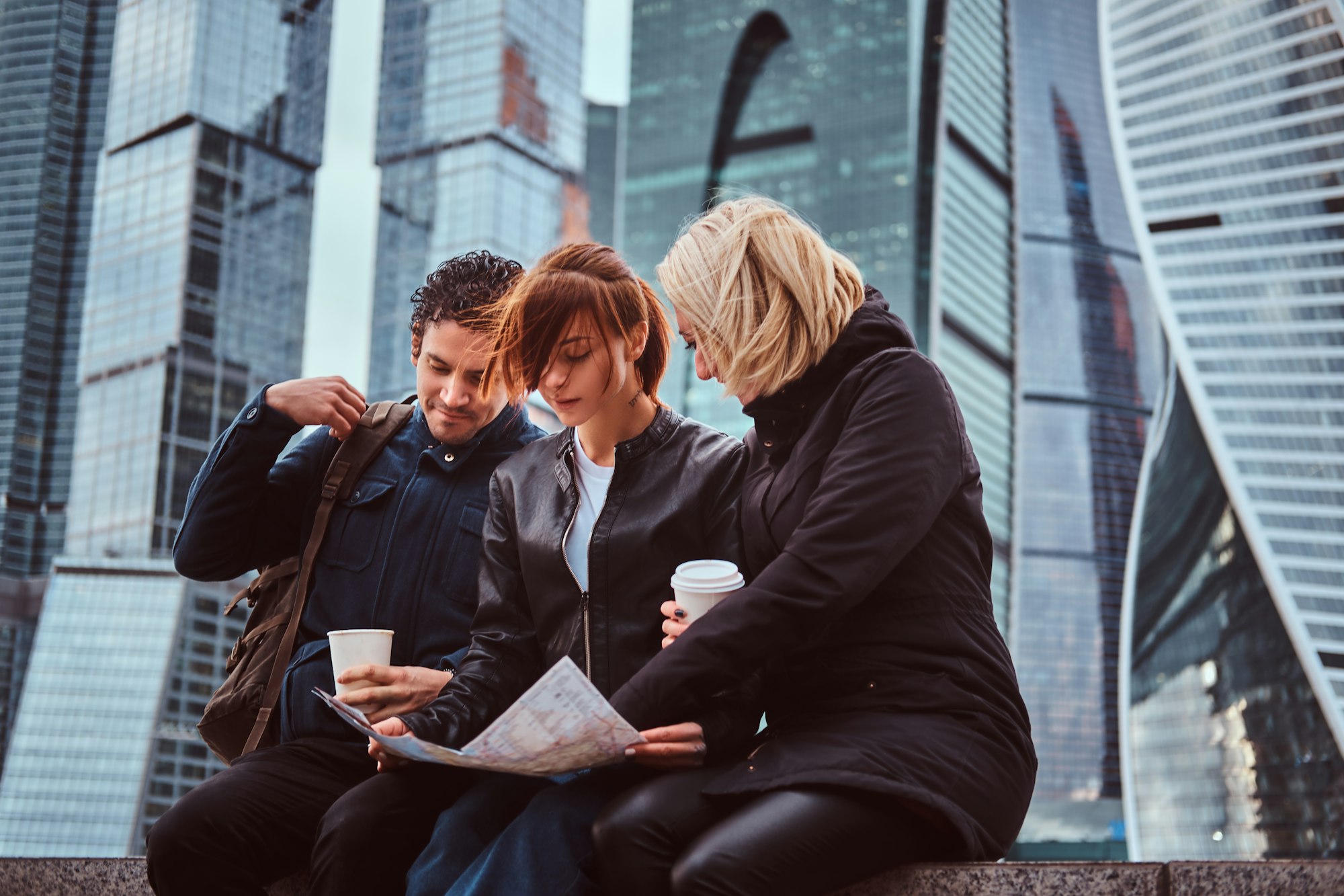 Group of tourists searching place on the map in front of skyscrapers