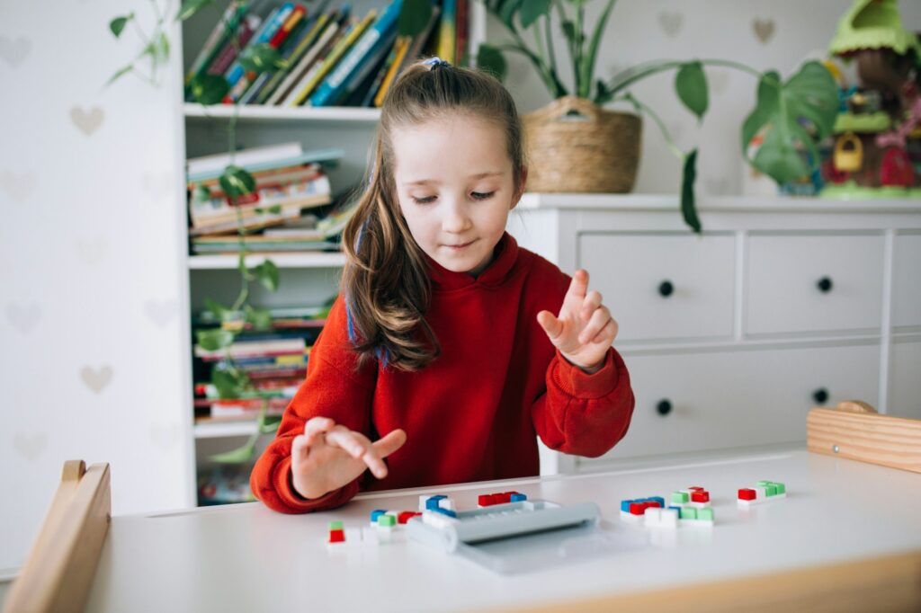 Happy girl sits at the table and plays an educational game, iq puzzle