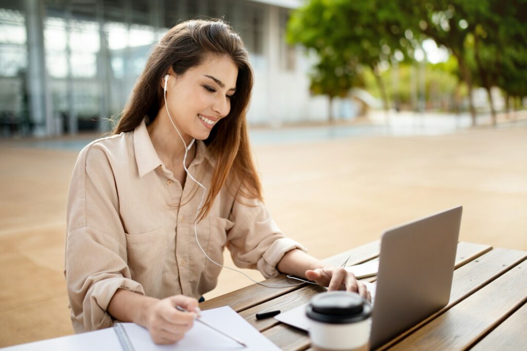 Happy student lady learning watching lecture online via laptop outdoor