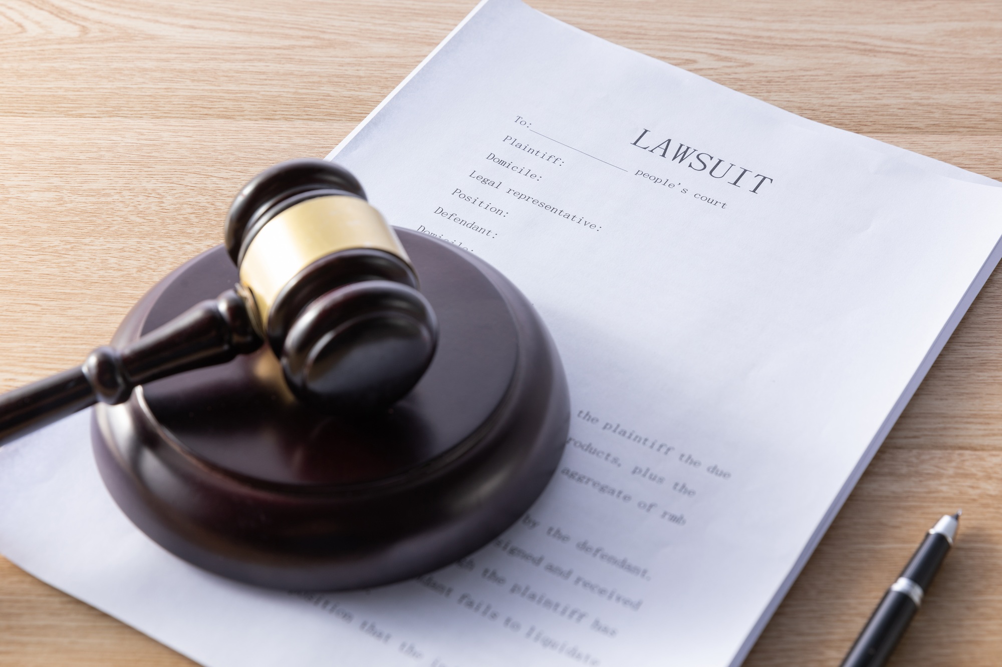 High angle shot of a gavel and lawsuit papers on a wooden surface