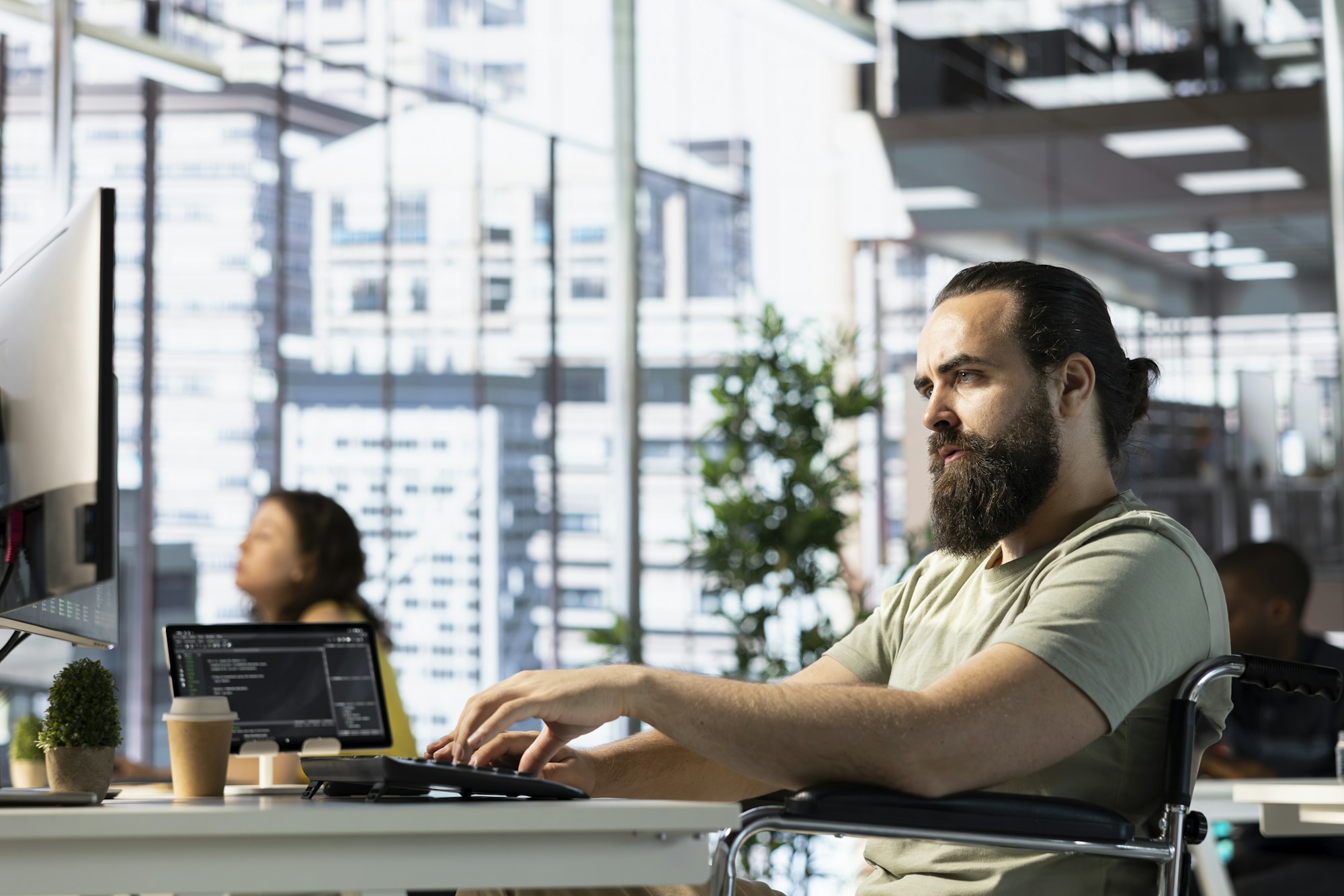 IT expert with disability programming in office, sitting in wheelchair