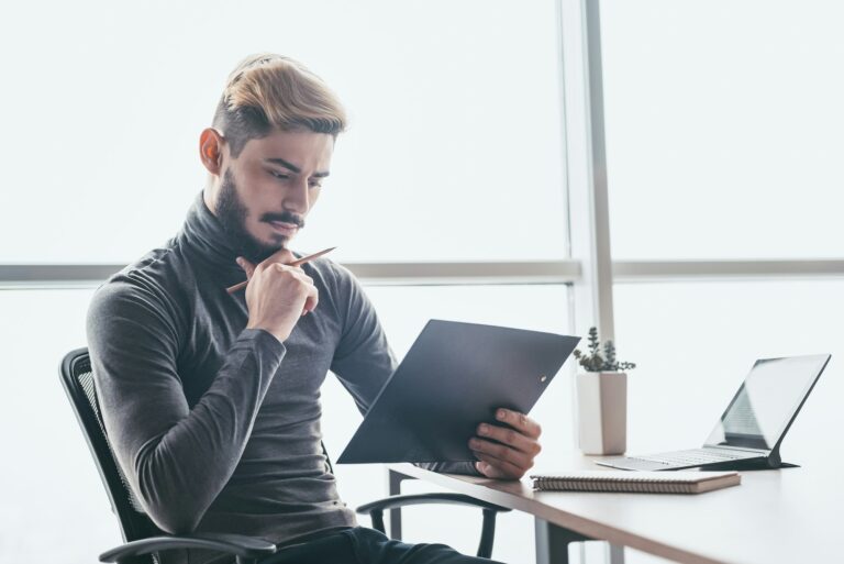 Pensive stylish businessman sitting at office desk