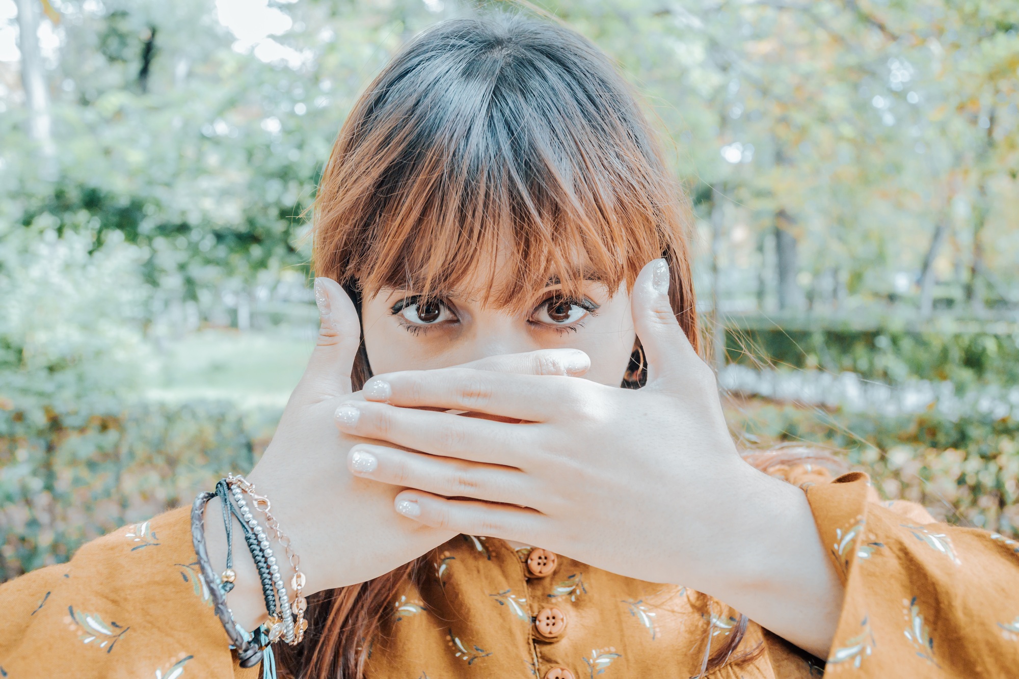 Portrait of a young red head woman covering his mouth with his hands, protest