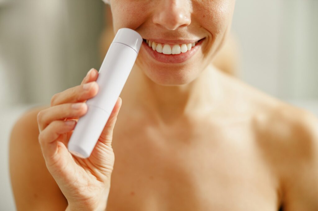 Smiling Woman Using a Skincare Device in a Beautiful and Relaxing Bathroom Setting