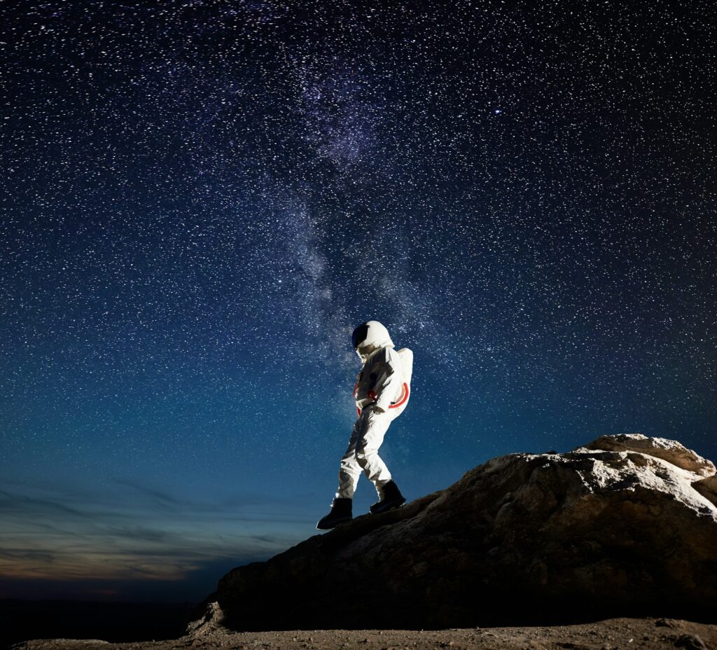 Space traveler walking down the mountain under starry sky.