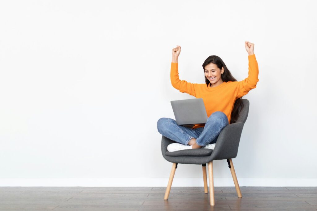 Thrilled young indian woman entrepreneur using laptop, white background