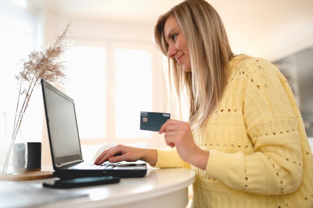 Young woman holding credit card and using laptop computer. Businesswoman working at home, e-commerce