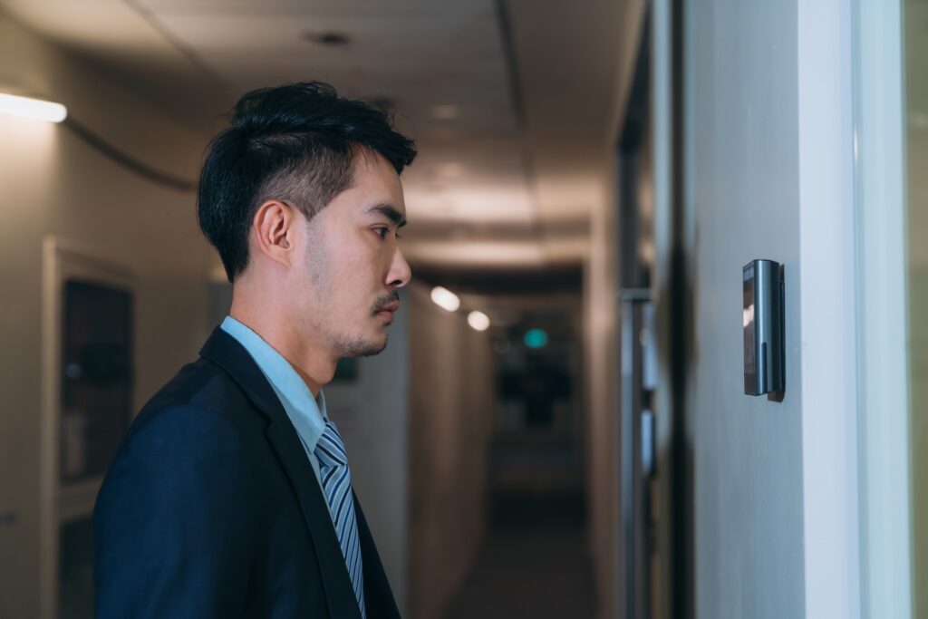 A face scanner being used by a man to open a door at an office building.