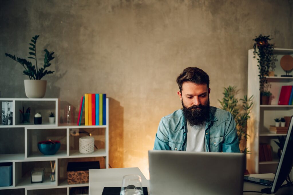 A focused bearded IT expert is sitting at his cozy home office and working on a new generation AI.