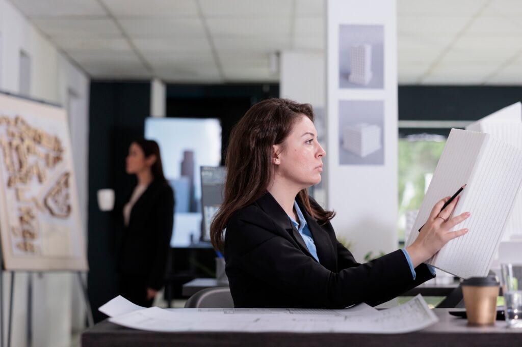 Architecture office employee looking at building 3d printed model