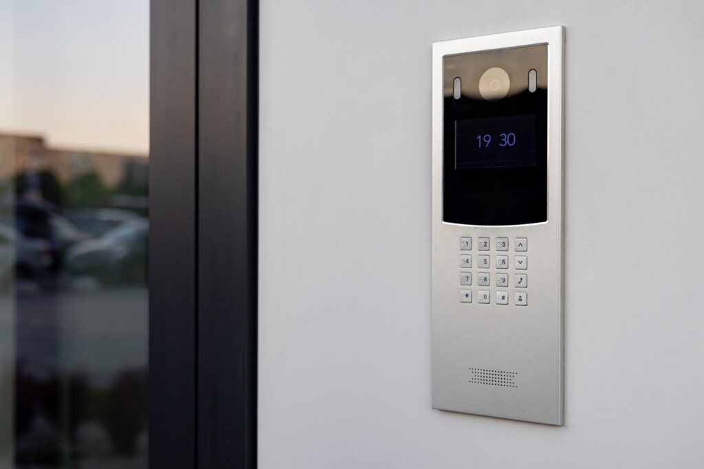 Doorbell with video camera and microphone, on the white wall of an apartment building, doorbell