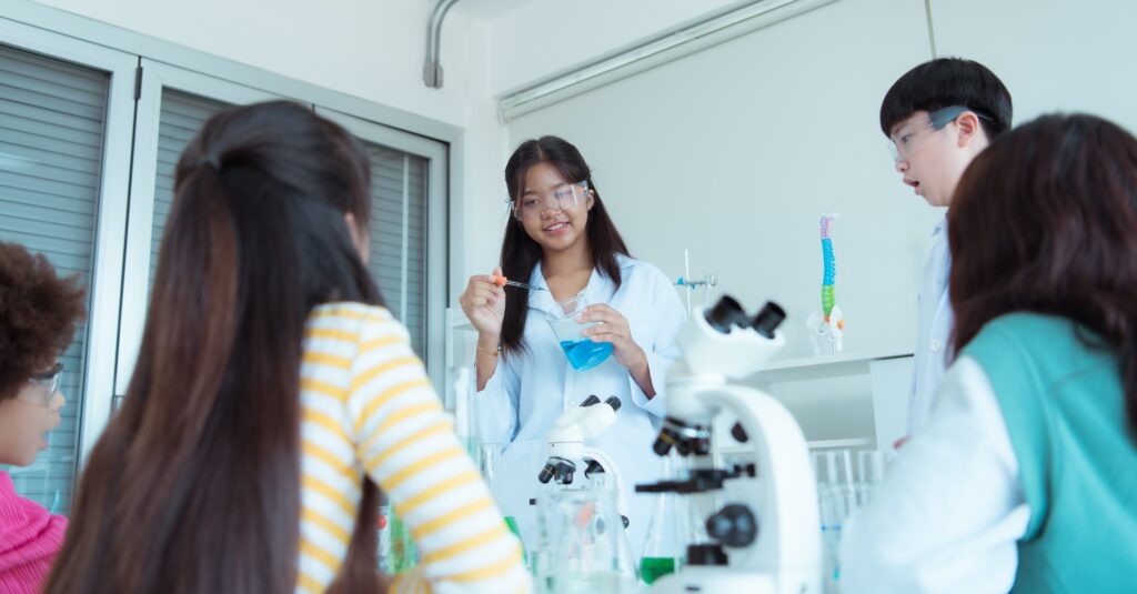 In the science classroom, an Asian child scientist experimenting with scientific formulas