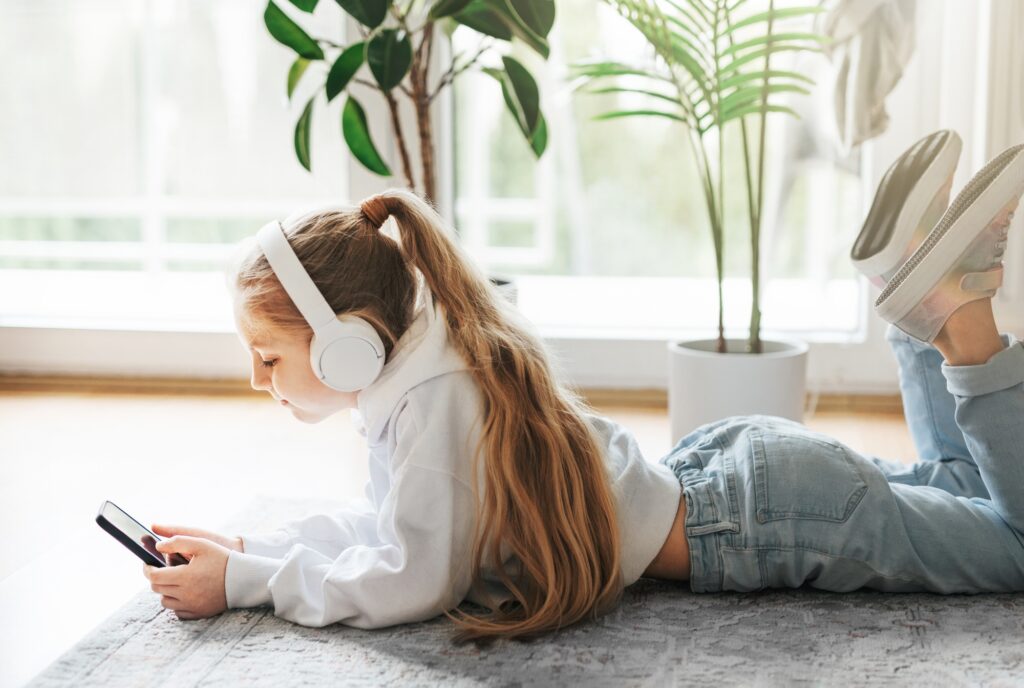 Little girl listening music lying on the floor