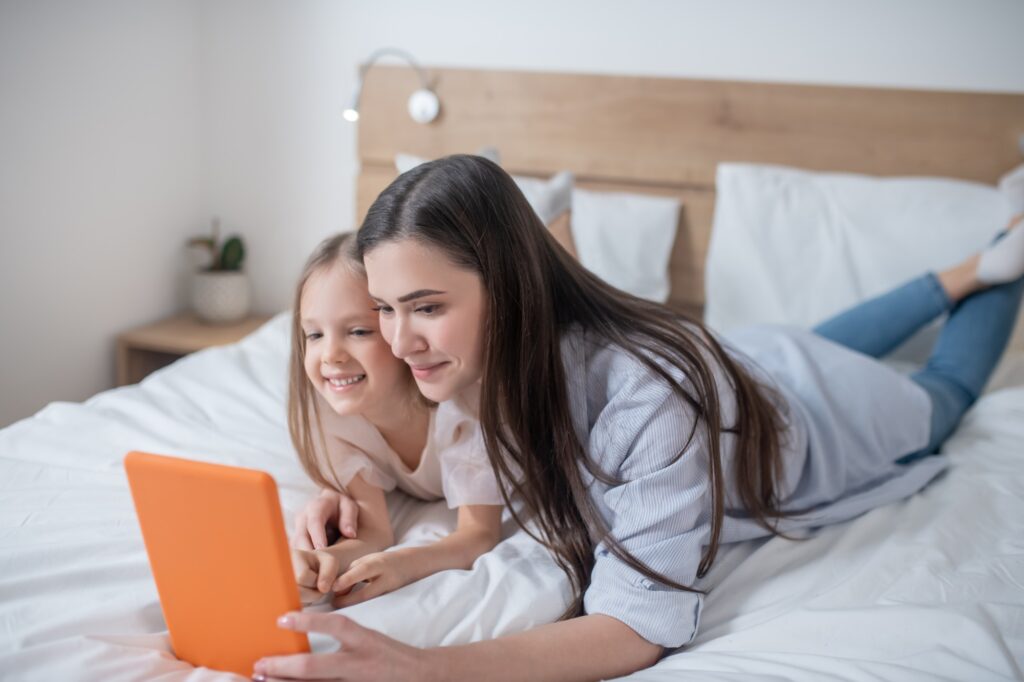 Mother entertaining her female child using a mobile device