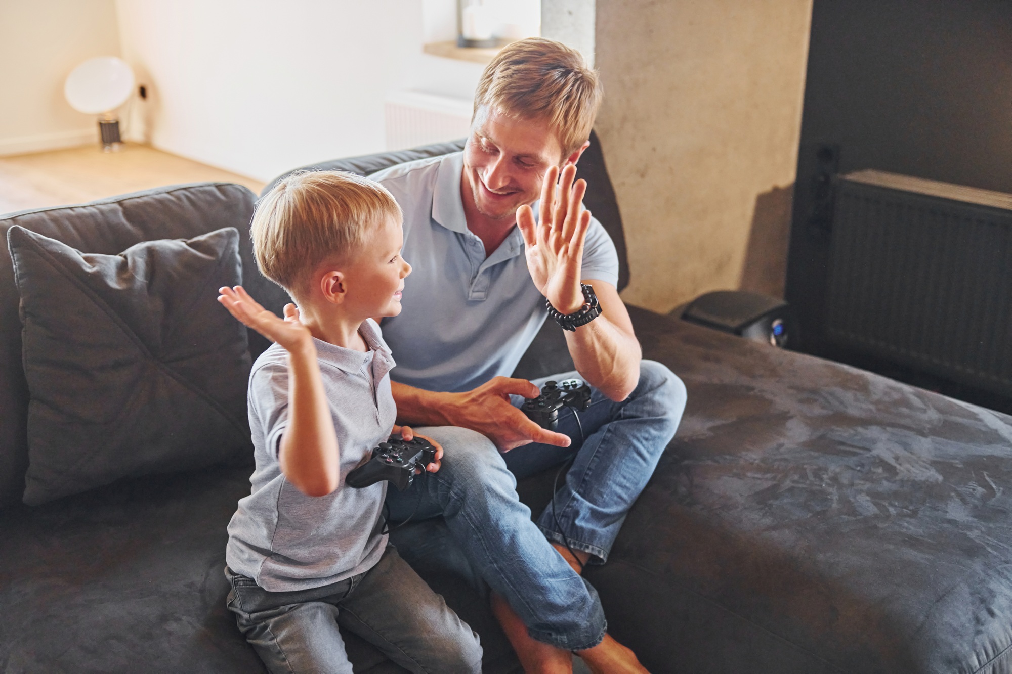 Playing video game. Father and son is indoors at home together