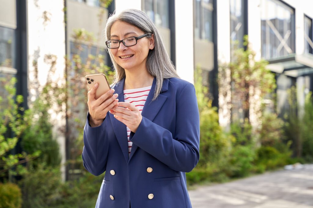 Pleased lady in business attire checking her phone updates