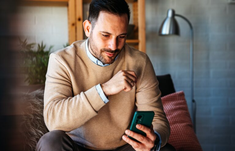 Portrait of a man using smart phone at home office. Work, freelance social media technology concept.