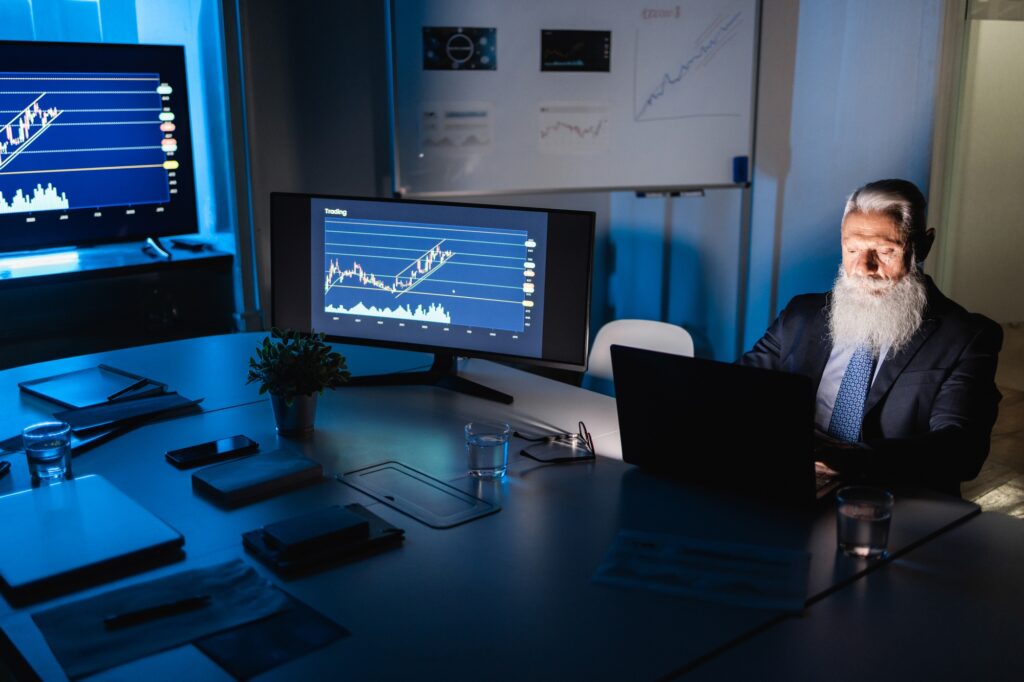 Senior business man working at night inside fintech company office