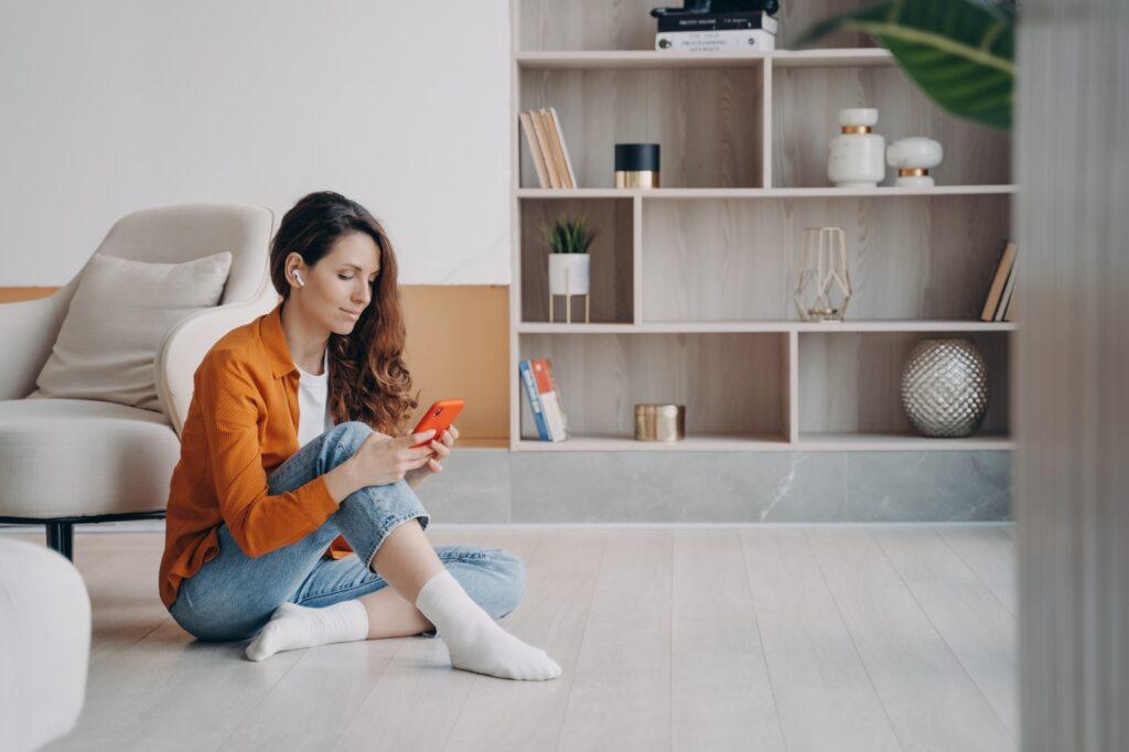 Trendy european woman is listening to music in airpods. Weekend morning relaxation.