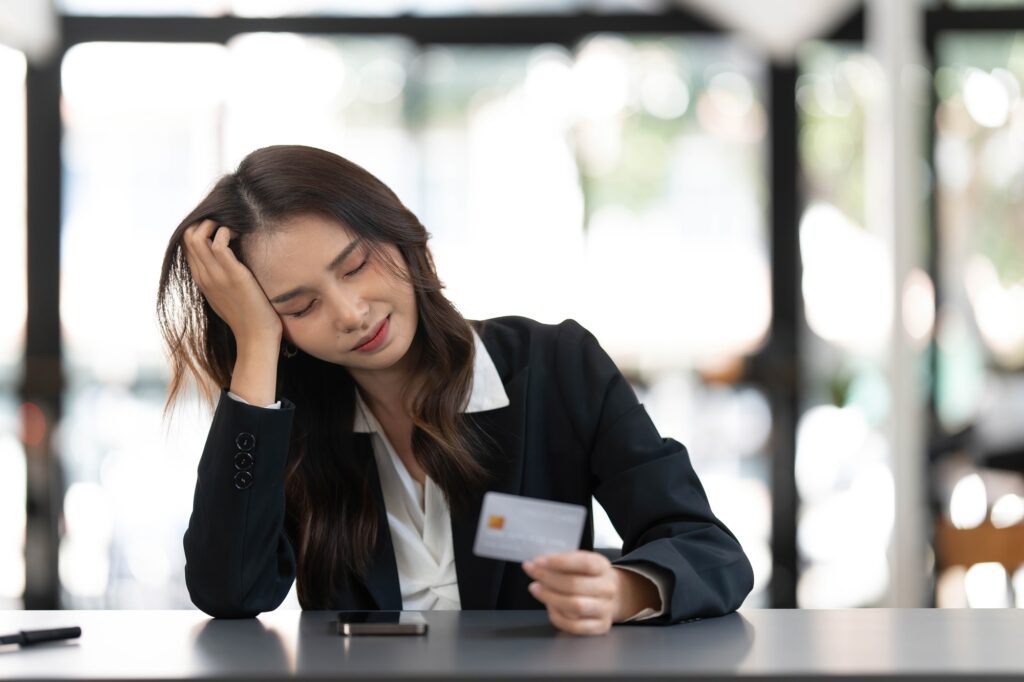 Unhappy young asian female buyer have problems buying online on internet on smartphone with credit