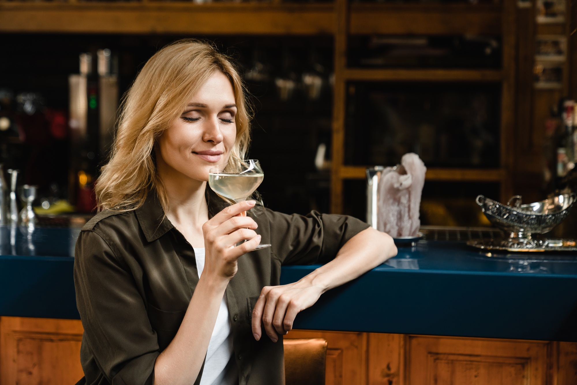 Woman smelling aroma drinking wine cocktail toasting celebrating event while chilling at bar counter