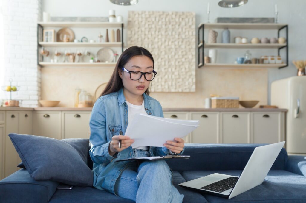 Young woman Asian writer. journalist. He sits at home with a laptop and writes a book, an essay