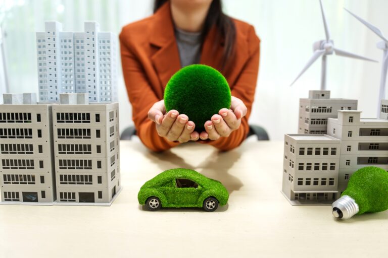 A young businesswoman works at a white desk with city buildings, solar cells, a wind turbine