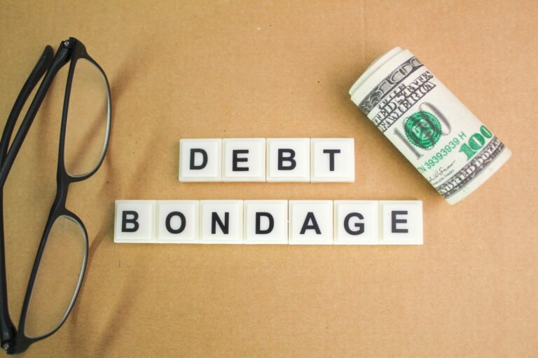 glasses and a roll of paper money with the word debt bondage