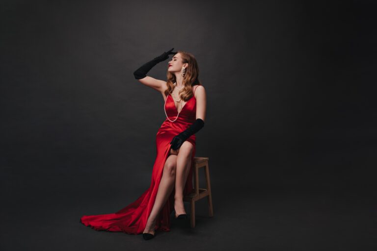 Hollywood celebrity in red dress posing on black background