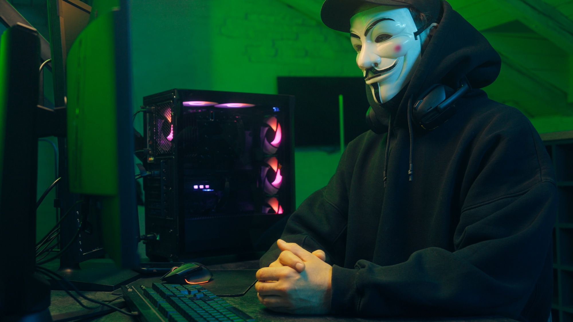 Lviv, Ukraine - June 03, 2024: Masked man anonymous stretching fingers programmer hacking typing