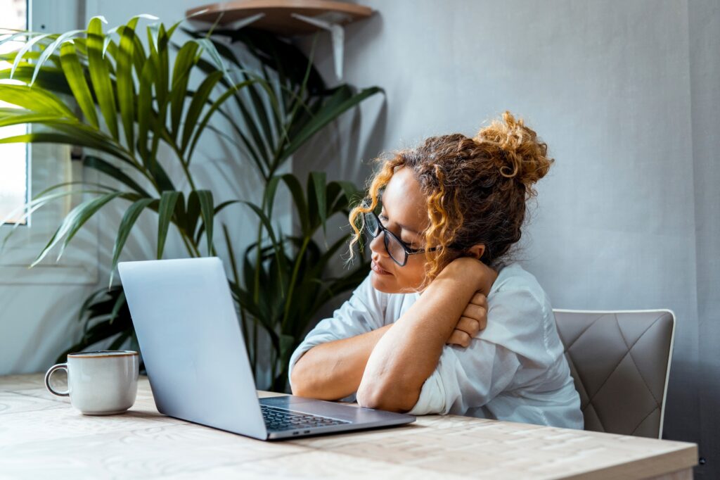 One tired and bored woman in front of a laptop in home office workplace. Online business job.