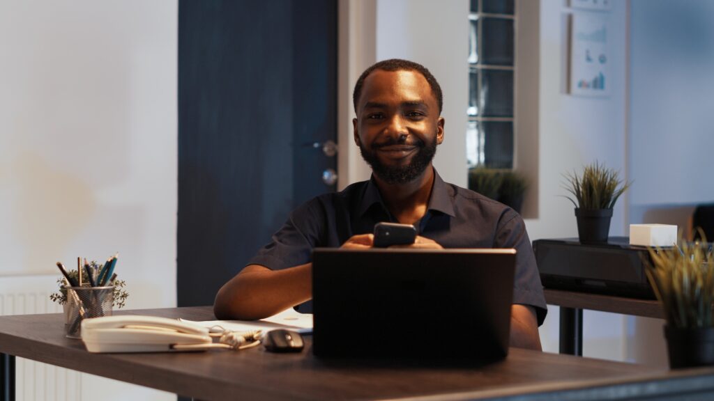 Portrait of smiling disruptive employee texting messages on smartphone