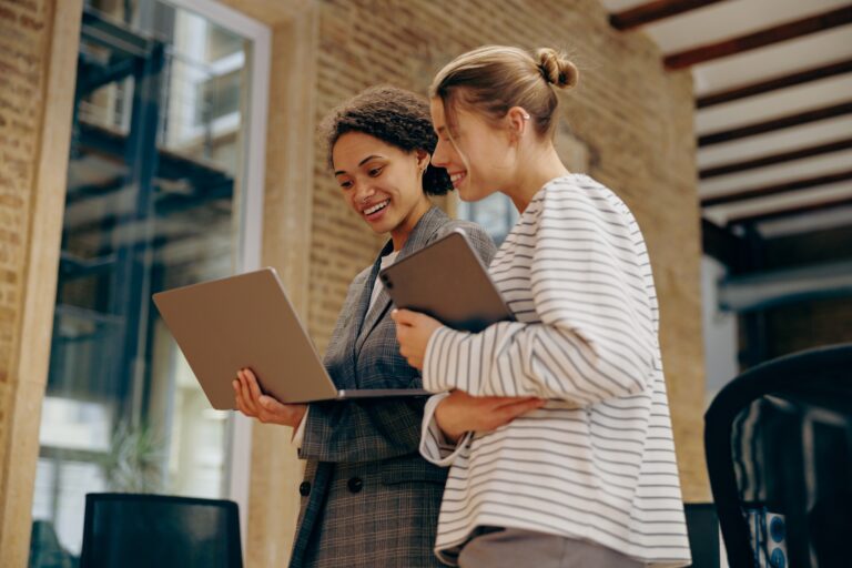 Two business woman work together to get the job done at the office and use laptop