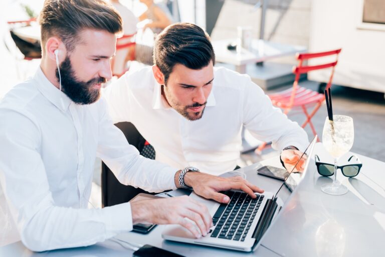 two businessmen outdoor using technology