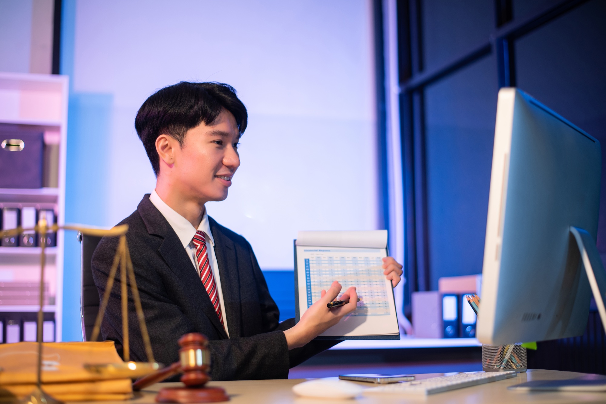 asian male lawyer chatting online with client on laptop, smartphone discussing details of lawsuit