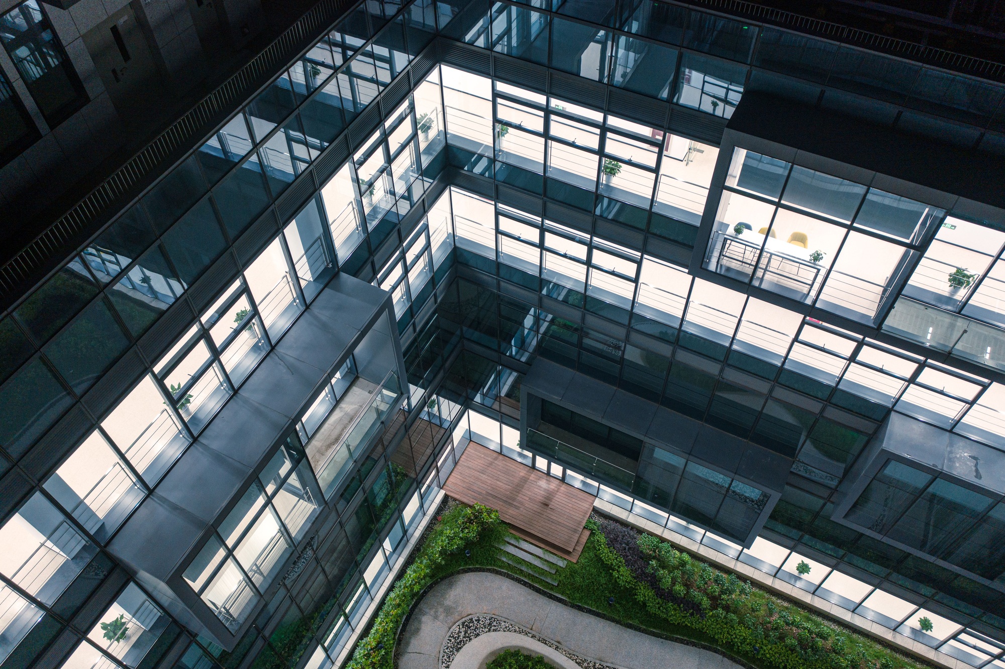 courtyard garden of a high tech company has a curved passage surrounded by transparent glass walls.